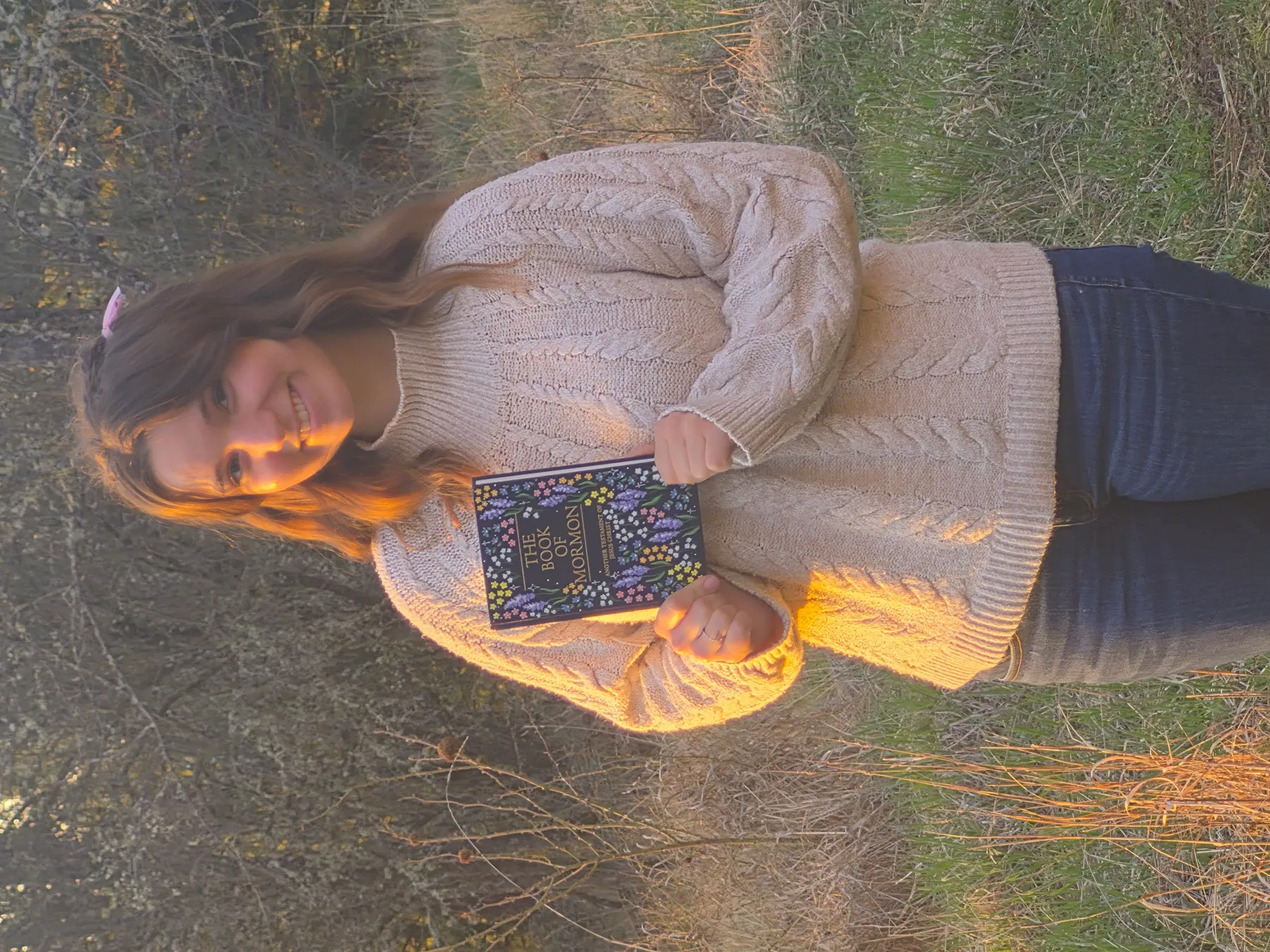 The artist holding a hand-painted Book of Mormon